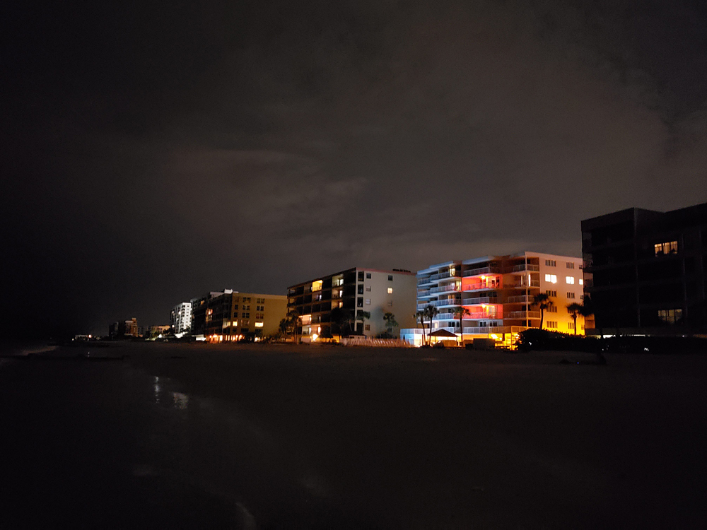 a row of lit-up hotels along a beach after sundown