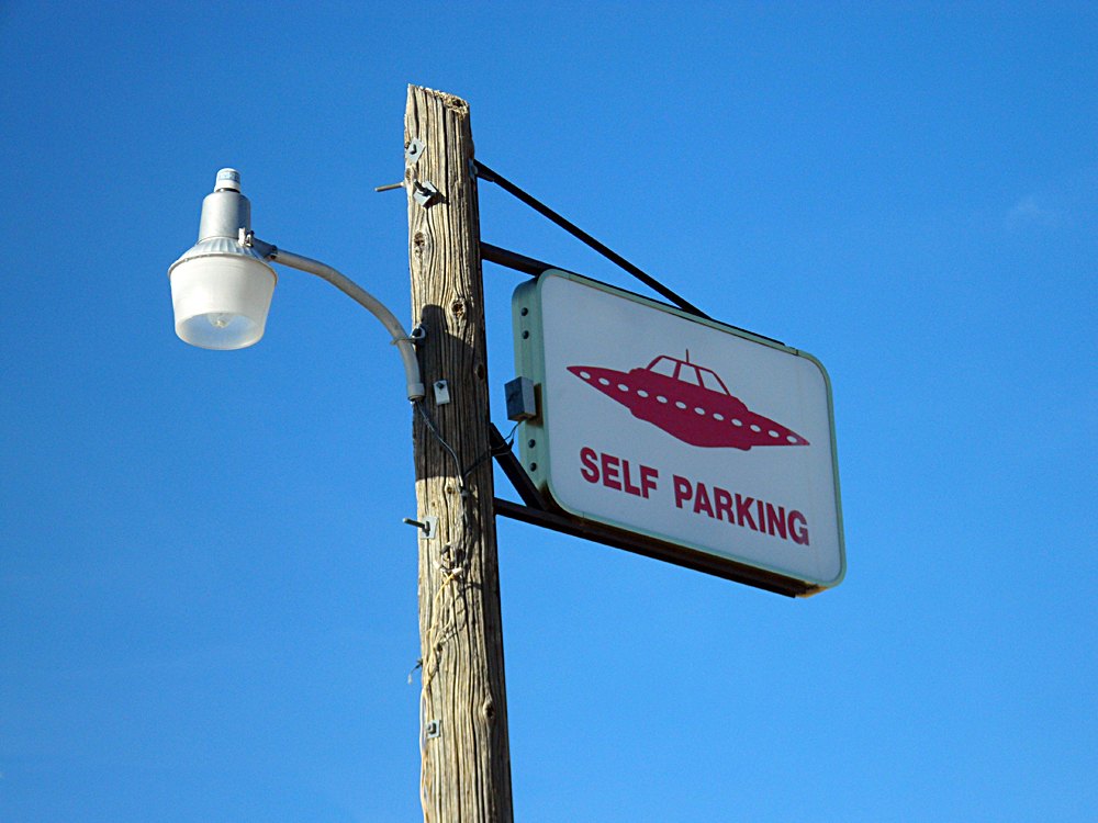 A self parking sign featuring a flying saucer