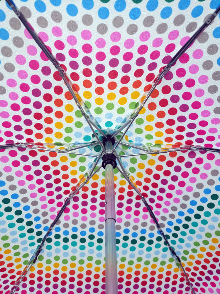 the underside of a white umbrella with rainbow polka dots
