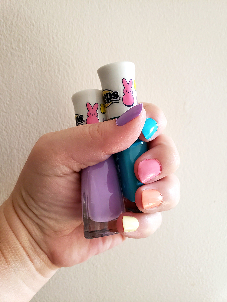 a hand holding two bottles of 'Peeps' nail polish; each fingernail is painted a different shade